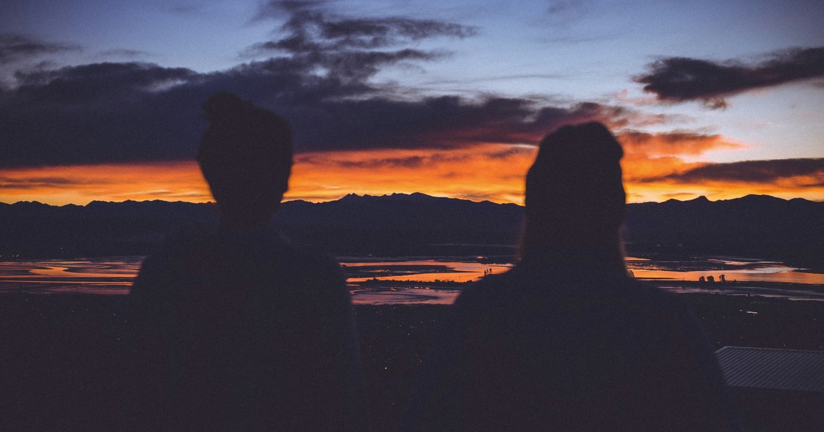 couple de femmes tendrement enlacees dans un lit, lumiere douce, intimite lesbienne