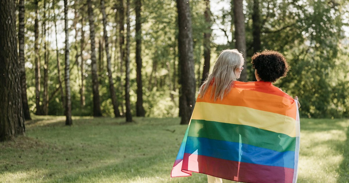 Couple de femmes enlacées dans un drapeau arc-en-ciel, symbole du soutien au mariage homosexuel aux États-Unis